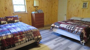 A room with two beds, wooden walls, a dresser, a window, and a door. - Just 15 minutes from Ricketts Glen State Park, Restaurant and Bed & Breakfast  (Benton)