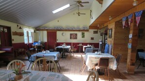 A restaurant with multiple tables and chairs, a ceiling fan, and a wooden interior. - Just 15 minutes from Ricketts Glen State Park, Restaurant and Bed & Breakfast  (Benton)