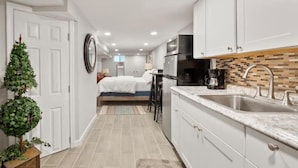 A compact kitchen with white cabinets, a countertop with a sink, and a coffee maker. - The Delightful Den (Philadelphia)