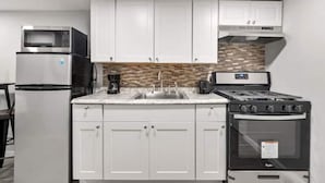 A kitchen with white cabinets, a microwave, a stove, and an oven. - The Delightful Den (Philadelphia)