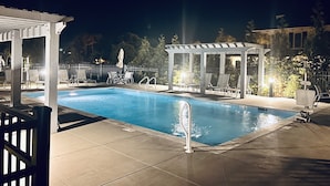 A nighttime swimming pool area with lounge chairs and a covered seating area. - *New* Oceanside,Pool,Walk 2 the beach,No Stairs (Corolla)