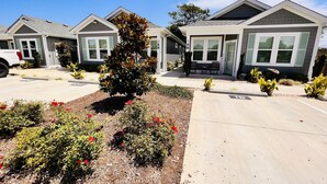 A row of modern, single-story houses with a landscaped front yard featuring red flowers and shrubs. - *New* Oceanside,Pool,Walk 2 the beach,No Stairs (Corolla)