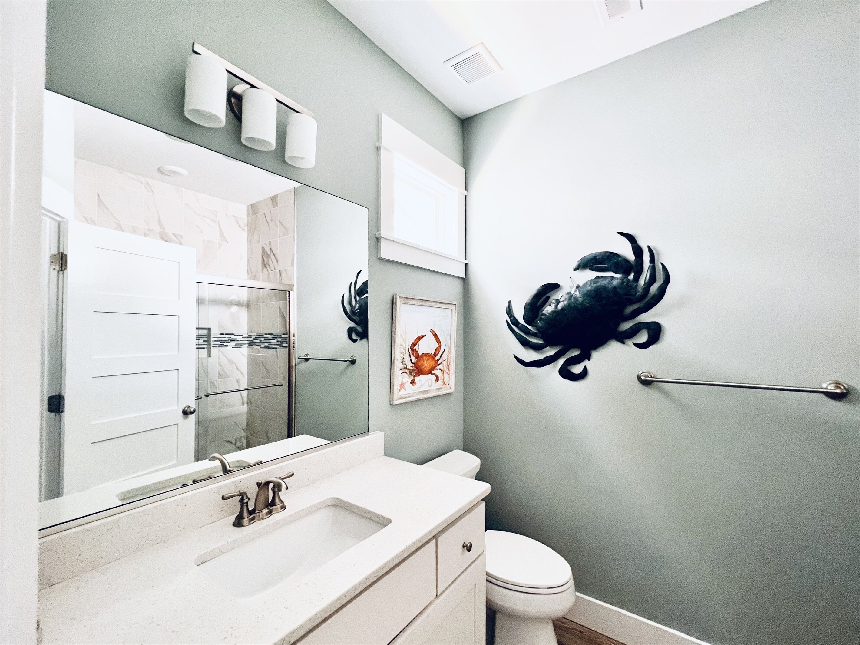 A bathroom with a white sink, a mirror, a toilet, and a wall-mounted towel dispenser.