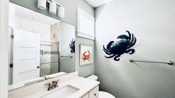 A bathroom with a white sink, a mirror, a toilet, and a wall-mounted towel dispenser.
