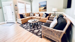 A living room with a sectional sofa, a coffee table, a wicker chair, and a ceiling fan. - *New* Oceanside,Pool,Walk 2 the beach,No Stairs (Corolla)