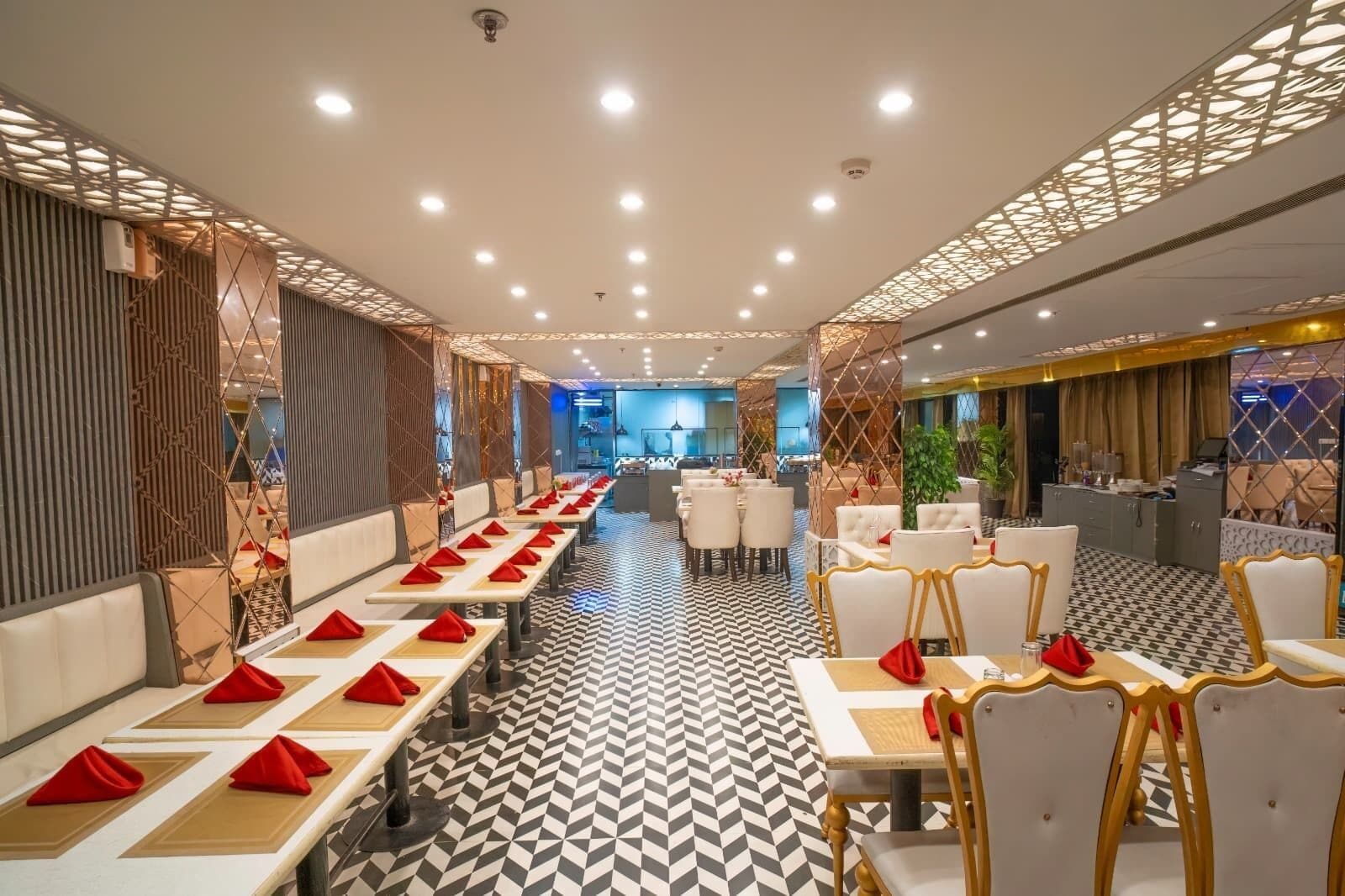 Un restaurante moderno con largas mesas compartidas y cabinas, un suelo con estampado y un techo con iluminación empotrada.