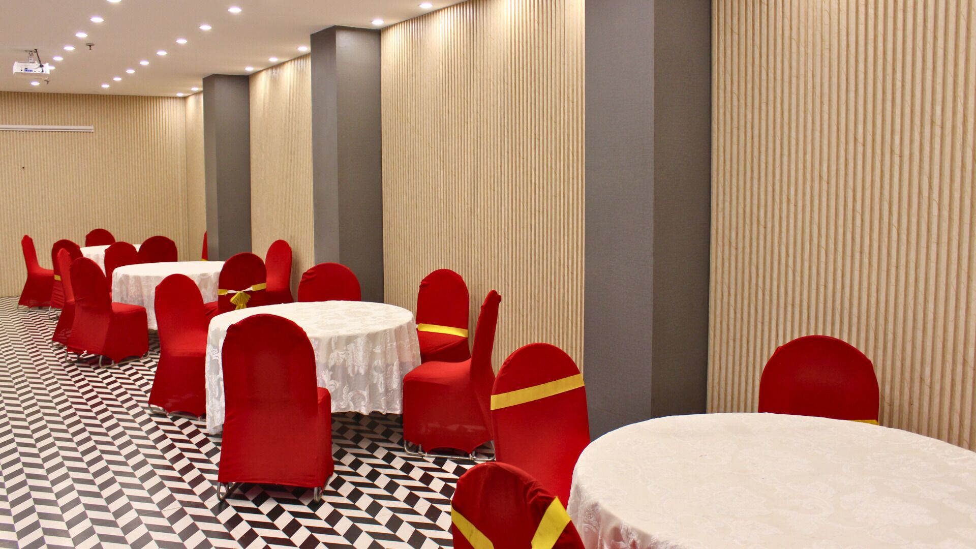 A conference room with round tables, red chairs, and a patterned floor.