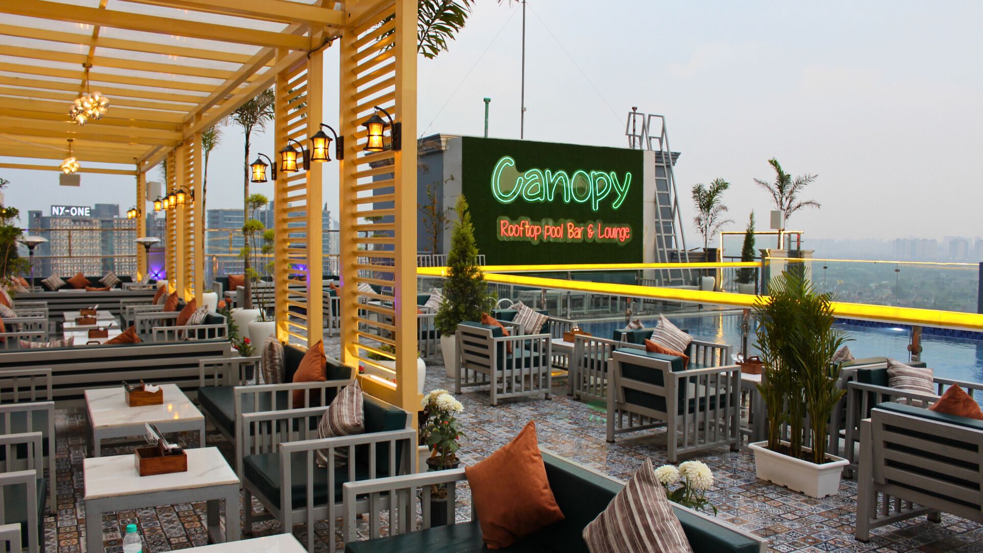 Un bar-terraza junto a la piscina en la azotea, con asientos al aire libre y un letrero de neón.