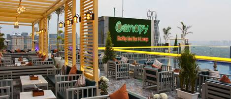 Un bar-terraza junto a la piscina en la azotea, con asientos al aire libre y un letrero de neón.