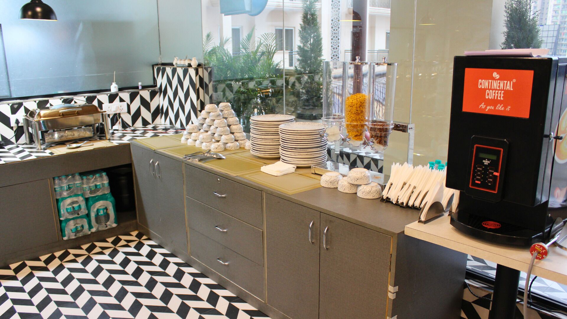 A coffee station with a coffee machine, stacks of plates, and a variety of condiments.