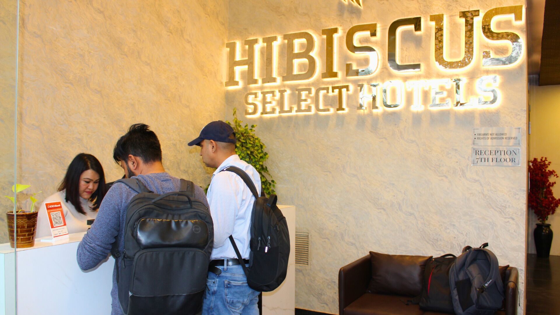 A reception desk at Hibiscus Select Hotels with a sign indicating the reception is on the 7th floor.