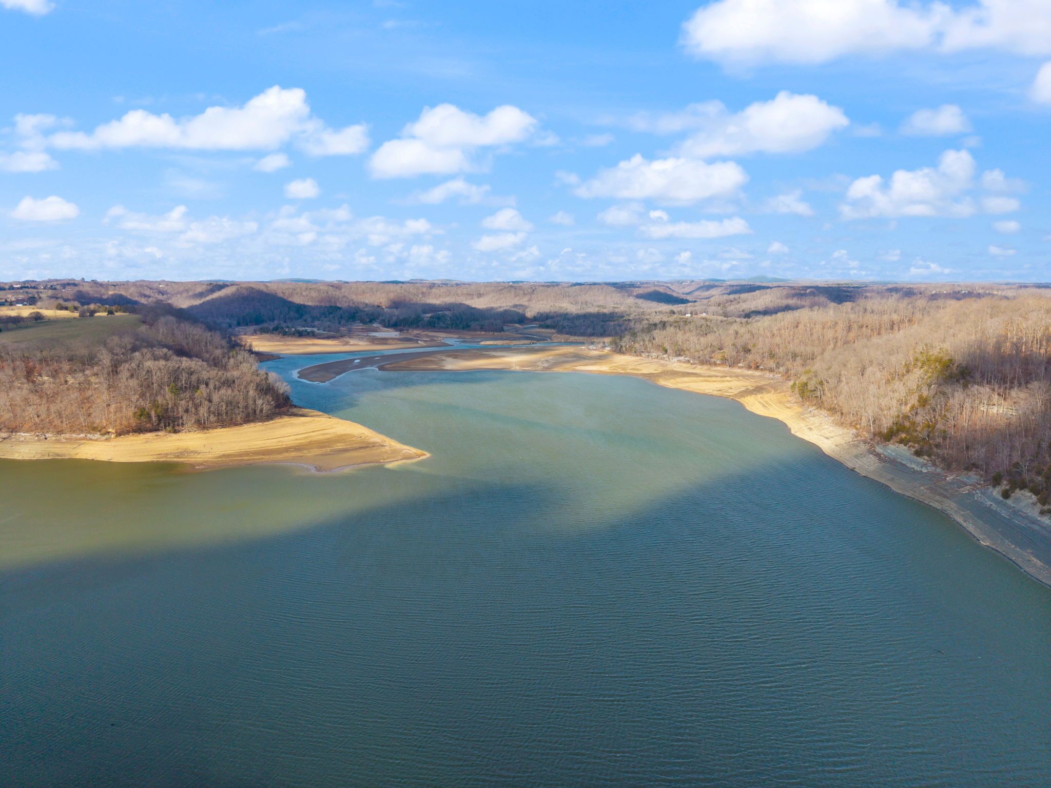 A river meandering through a landscape with hills and sparse vegetation.