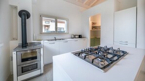 A modern kitchen with a gas stove, oven, and a chimney. - La Casa di Antonietta (Udine)