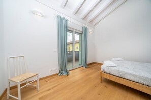 Een slaapkamer met een houten bed, een stoel, een schuifdeur en een dakraam.