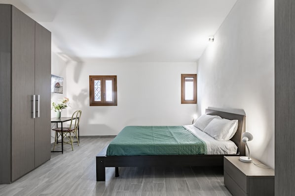 A bedroom with a bed, bedside table, lamp, and a window.
