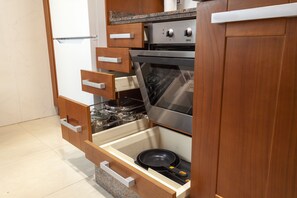 Una cocina con armarios de madera, horno de acero inoxidable y lavavajillas integrado.