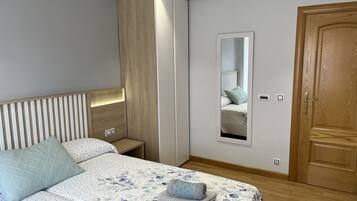 Een slaapkamer met een bed, een kledingkast, een spiegel en een deur.
