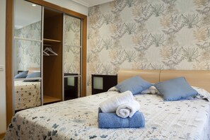 Un dormitorio con cama, dos almohadas, una toalla enrollada, un armario y un espejo.