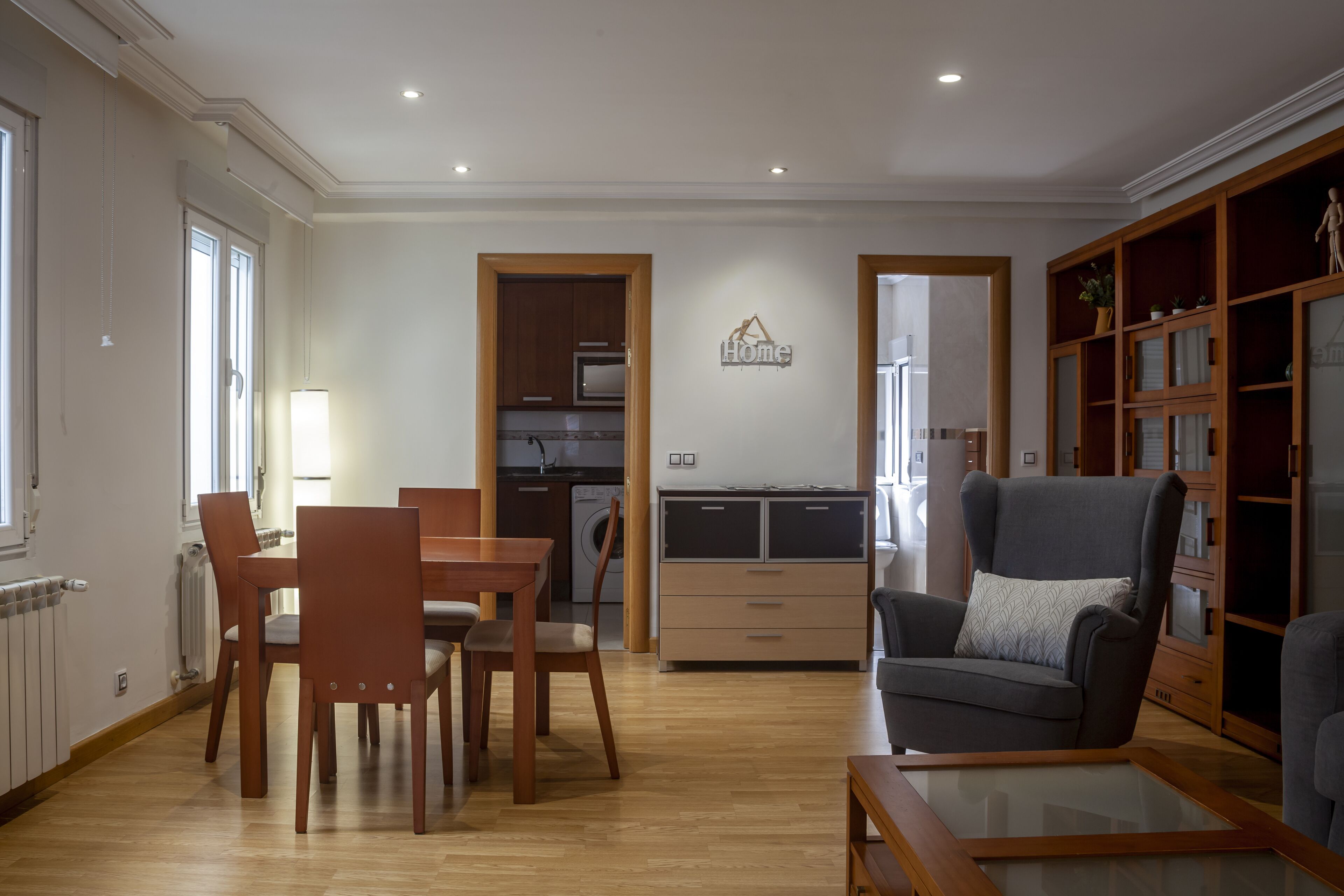 Amplia sala de estar con mesa de comedor, sillas, sofá y cocina al fondo.