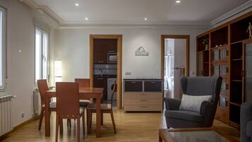 Amplia sala de estar con mesa de comedor, sillas, sofá y cocina al fondo.