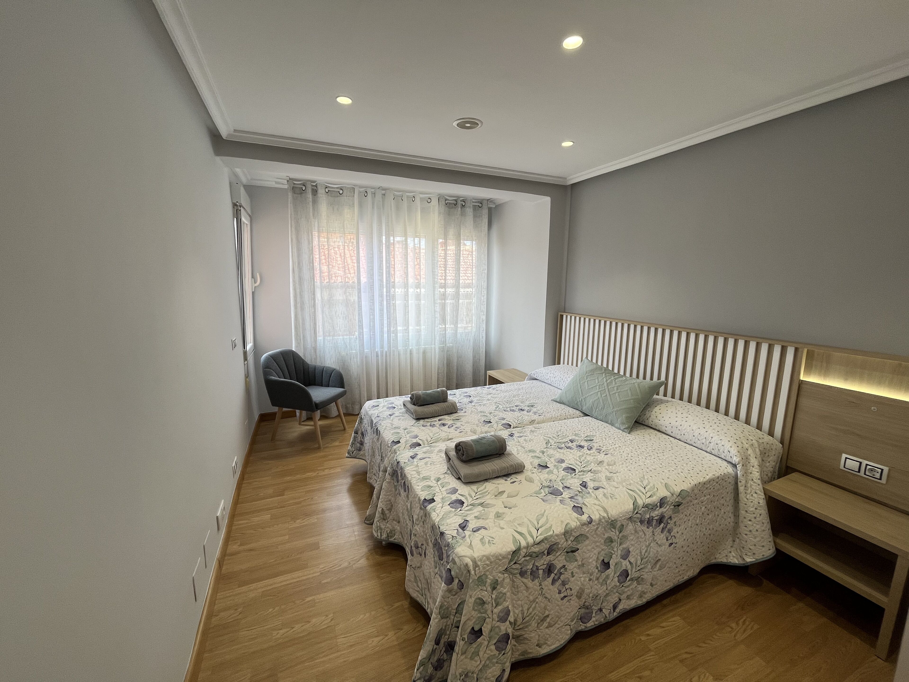 Une chambre à coucher moderne avec un grand lit, une chaise et une table de chevet.