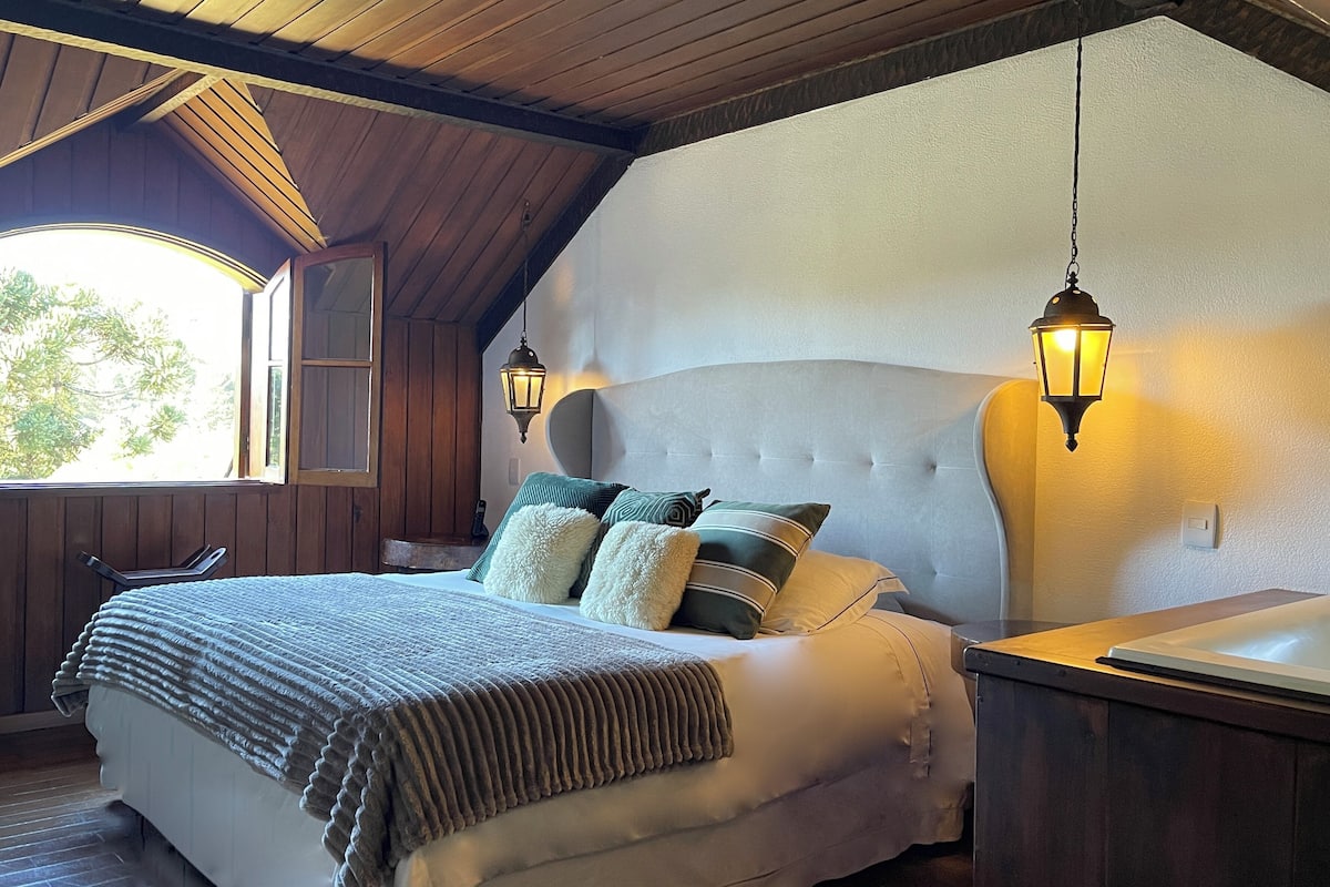 Un dormitorio con una cama grande, techo de madera y dos lámparas fijadas a la pared.
