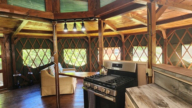 Una cocina rústica con estufa, lavabo y vigas de madera.