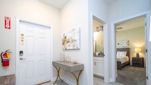 A hallway with a white door, a fire extinguisher, and a console table with a lamp. - Gorgeus HOUSE Near Disney & FREE water park 4963 (Kissimmee)