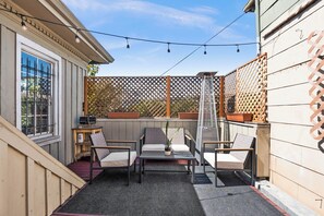 Relax in this serene outdoor patio, complete with a table, chairs, and lush greenery.