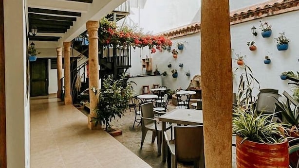 Un espacio al aire libre techado con suelo de baldosas, columnas de madera y plantas en macetas.