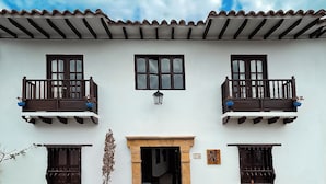 Un edificio de dos pisos con techo de tejas, una entrada central con arco de piedra y balcones con barandillas oscuras.