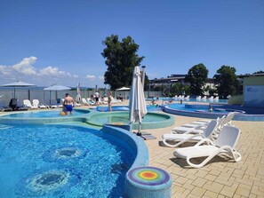 Et poolområde med flere pools, liggestole og parasoller.
