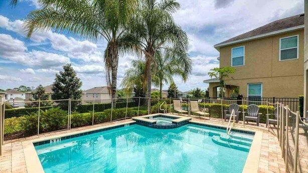A rectangular swimming pool with a hot tub, surrounded by a fence and palm trees. - Swift BnB - Taylor themed rooms - Pool - sleeps 16 (Kissimmee)