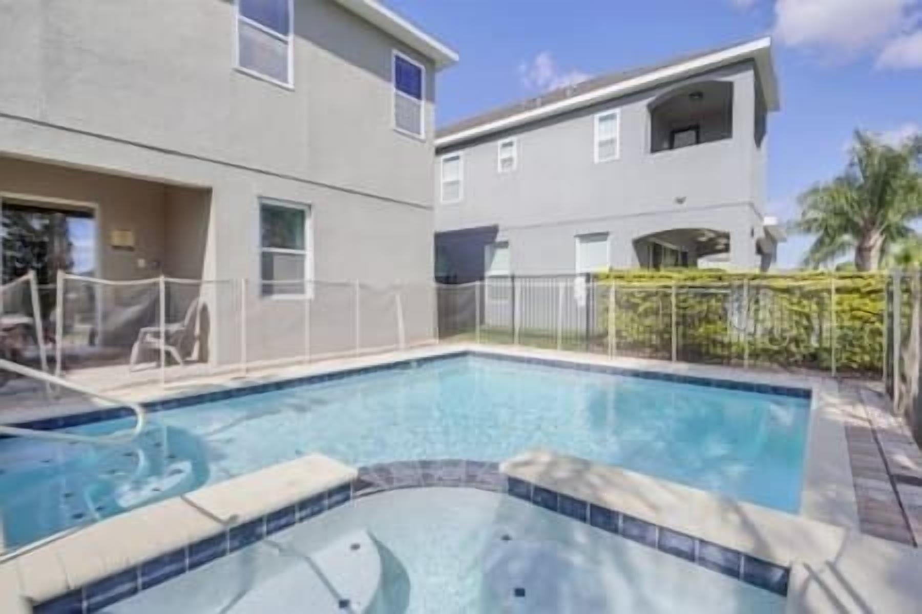 Une piscine avec une terrasse carrelée et un petit jacuzzi au centre.