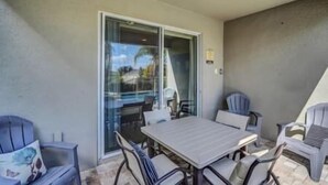 An outdoor patio area with a table and chairs, a sliding glass door, and a ceiling light fixture. - Swift BnB - Taylor themed rooms - Pool - sleeps 16 (Kissimmee)
