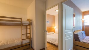 A room with bunk beds, a door leading to another room, and a lamp.