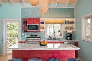 A kitchen with a large island, red cabinets, and a tiled backsplash. - Ocean Front: rooftop deck, generator & more! (Upper Bogue)
