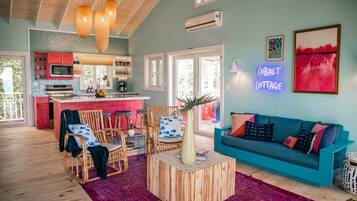 A cozy living area with a sofa, chairs, a coffee table, and a kitchen in the background.