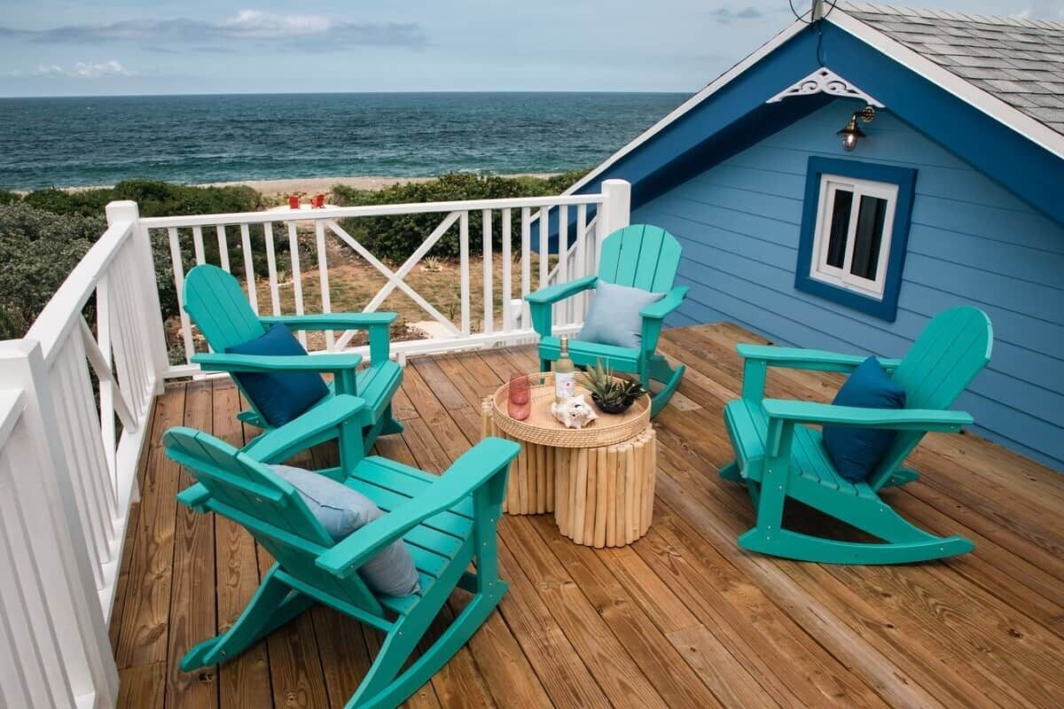 Une terrasse dotée de fauteuils à bascule et d’une petite table, offrant une vue sur l’océan.
