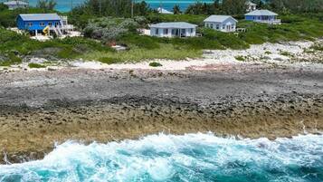 A beachfront property with multiple houses, a rocky shoreline, and the ocean.