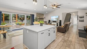 A spacious living area with a large island, a ceiling fan, and a view of the outdoors. - Tahoe Getaway | 2 King Suites & Hot Tub | Near Town, Lake Activities & Trails (Truckee)