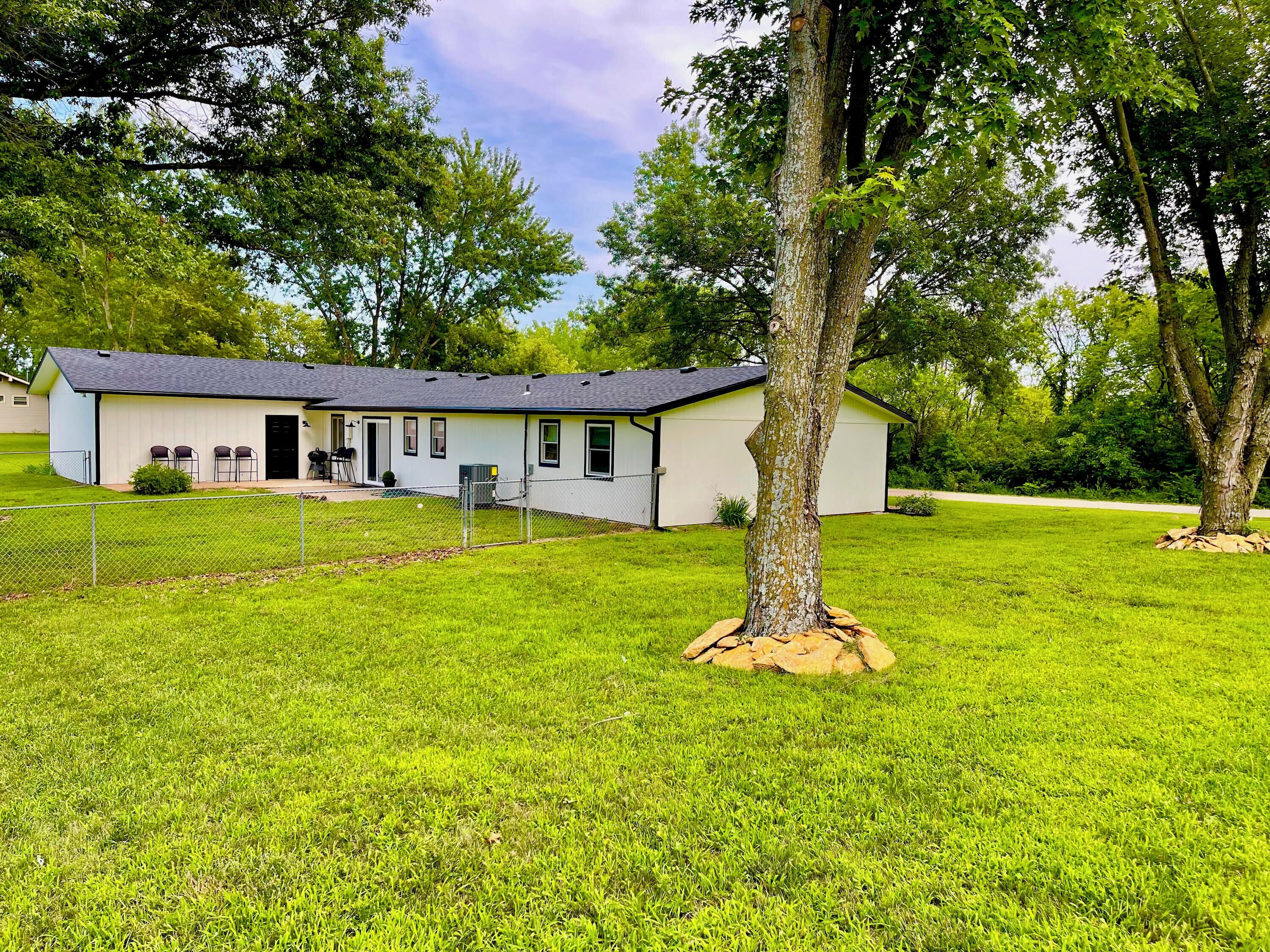 A single-story building with a flat roof, a covered porch, and a fenced yard.