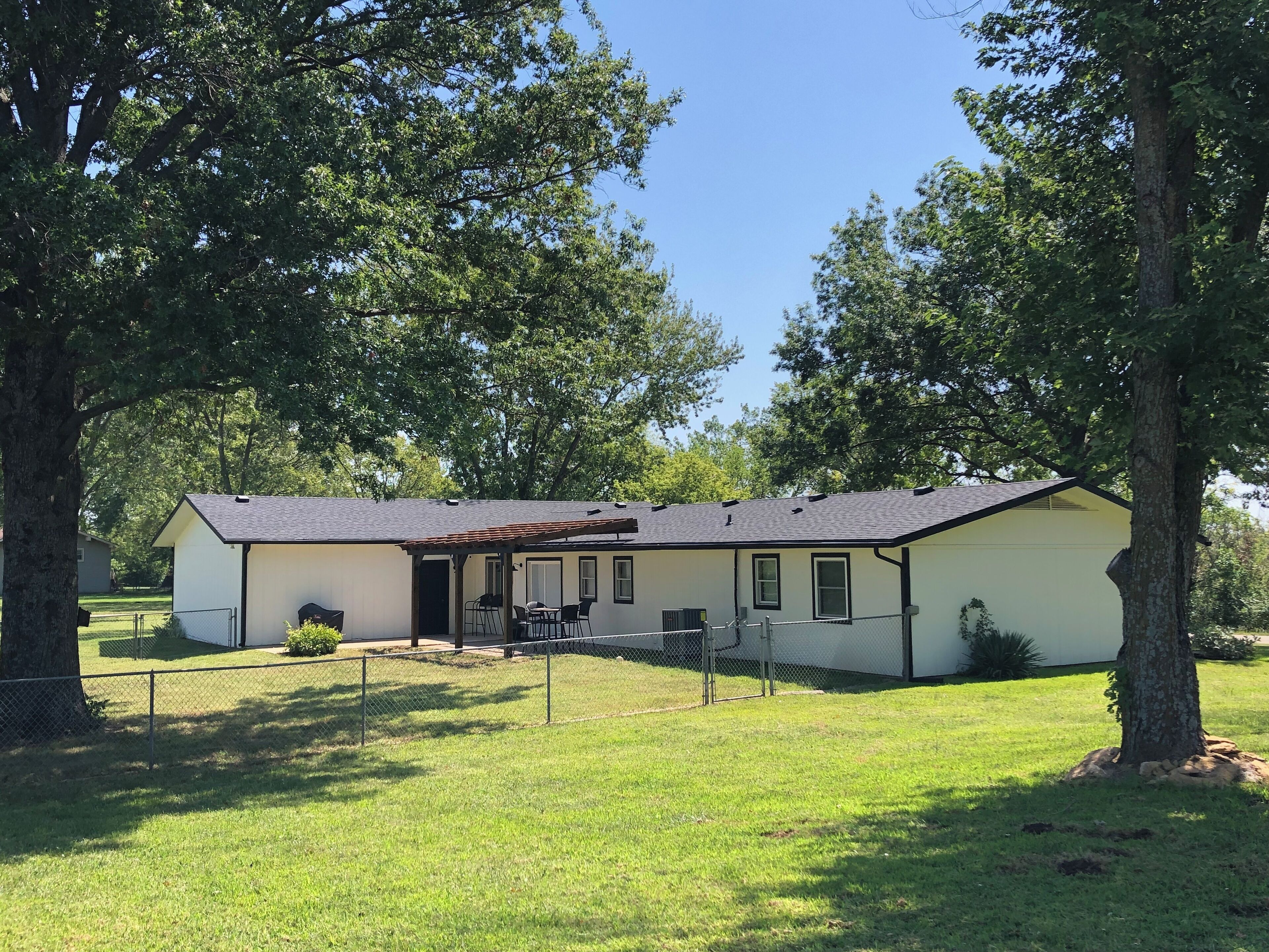 A single-story house with a fenced yard, a covered porch, and a small patio area.