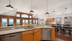 A spacious kitchen with granite countertops, wooden cabinets, and stainless steel appliances.