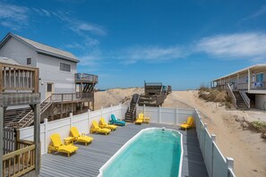 Ein Hotel direkt am Strand mit Poolbereich, Holzterrasse und Zugang zum Strand.