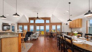 A spacious kitchen with a large island, wooden cabinets, and a dining area with a view of the ocean.