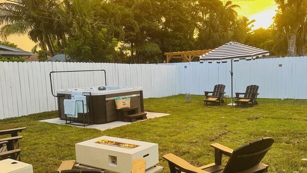 A backyard with a hot tub, outdoor seating, and a fire pit.