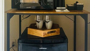 Een koffieapparaat, een magnetron en een koffiemachine op een houten tafel.