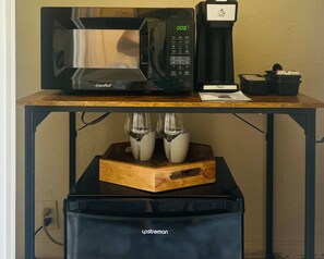 A coffee machine, a microwave, and a coffee maker on a wooden table.