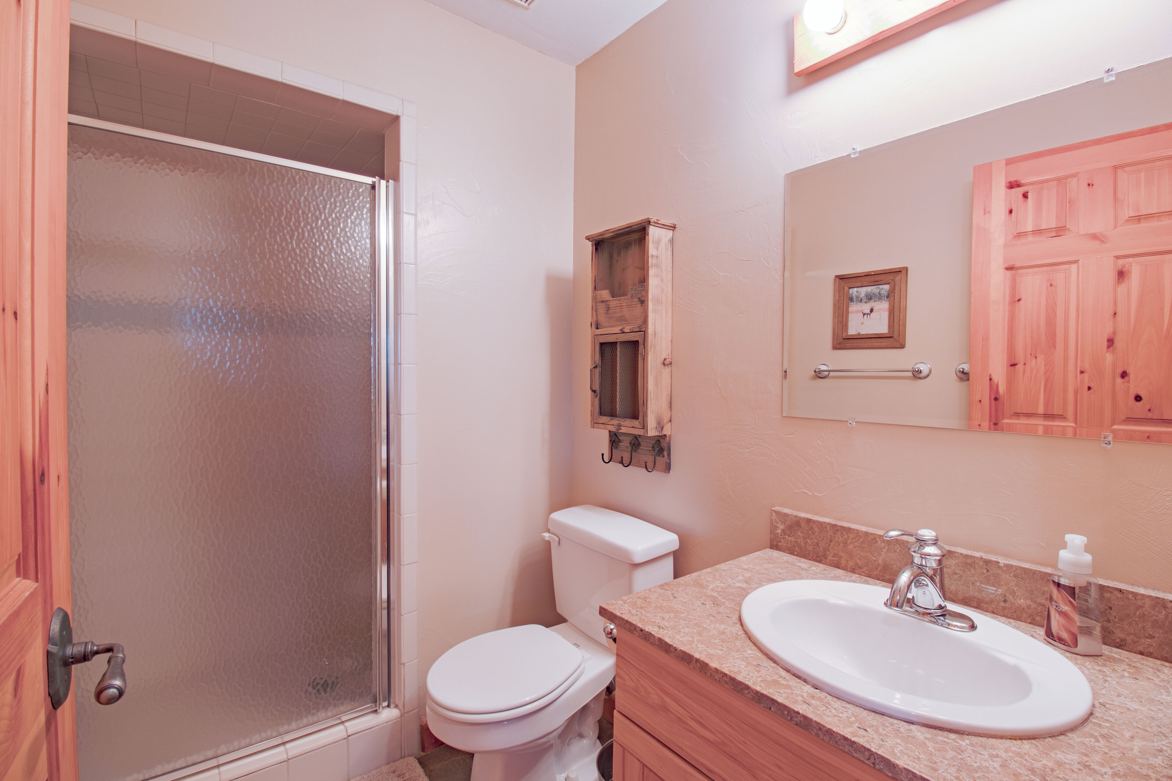 Un baño con ducha, inodoro, lavabo y armarios de madera.